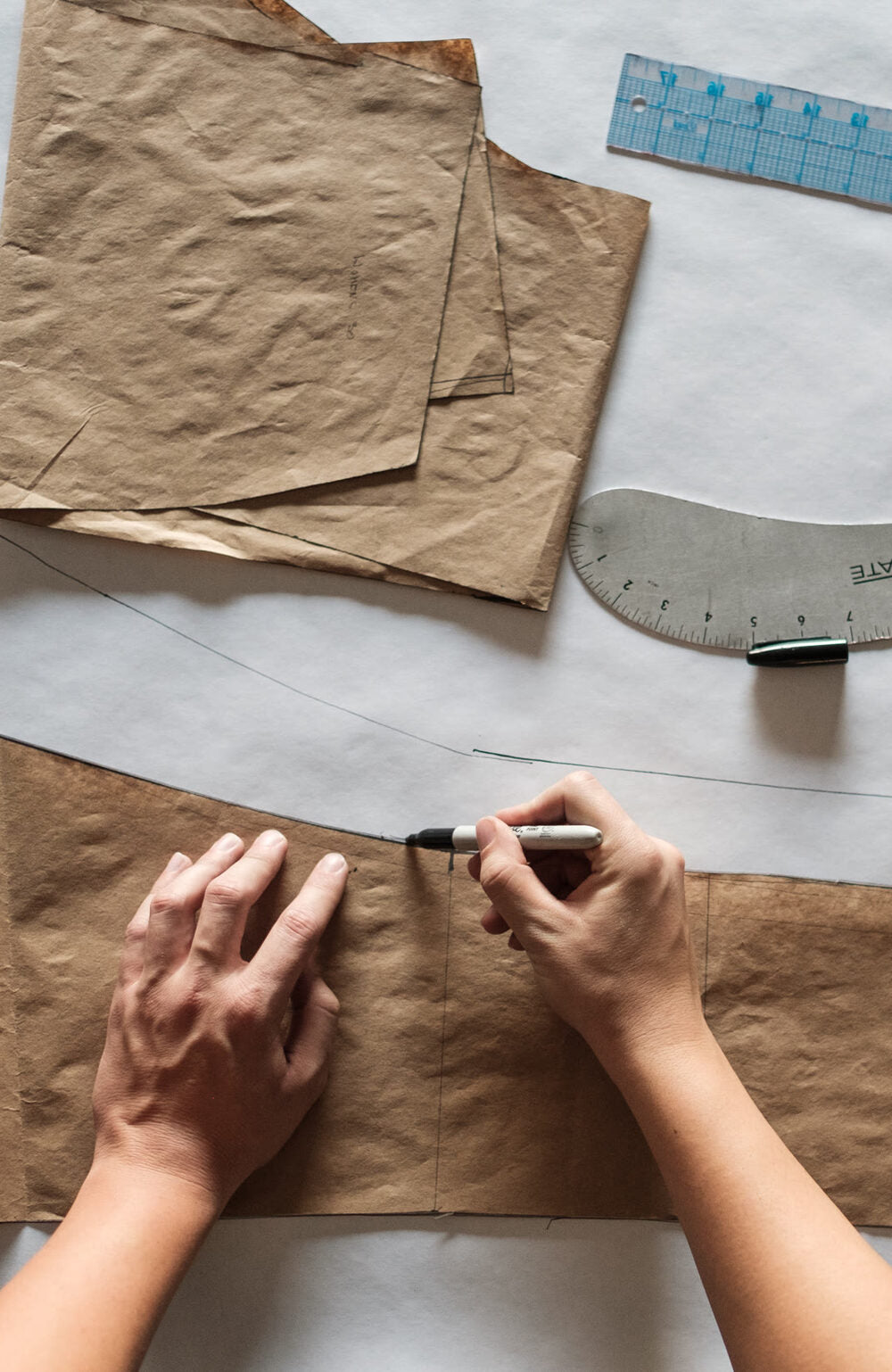 A pattern maker drafting a paper pattern on the cutting table