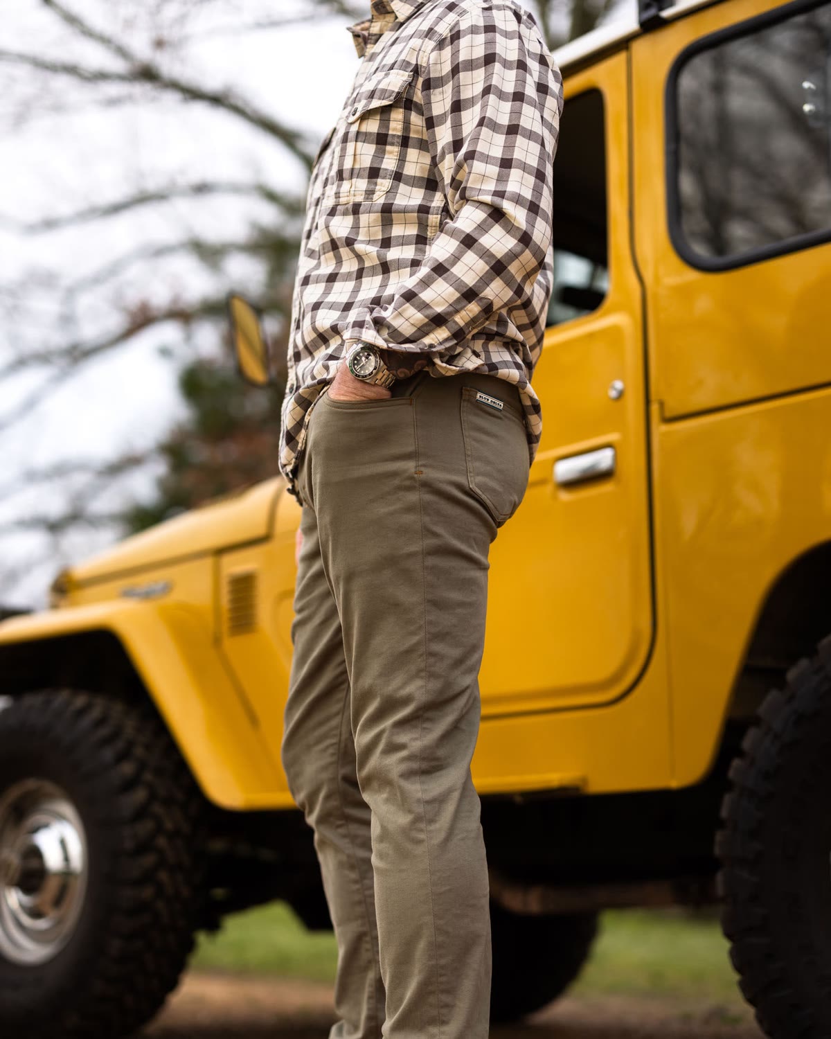Olive chinos and a plaid shirt beside a yellow Land Cruiser