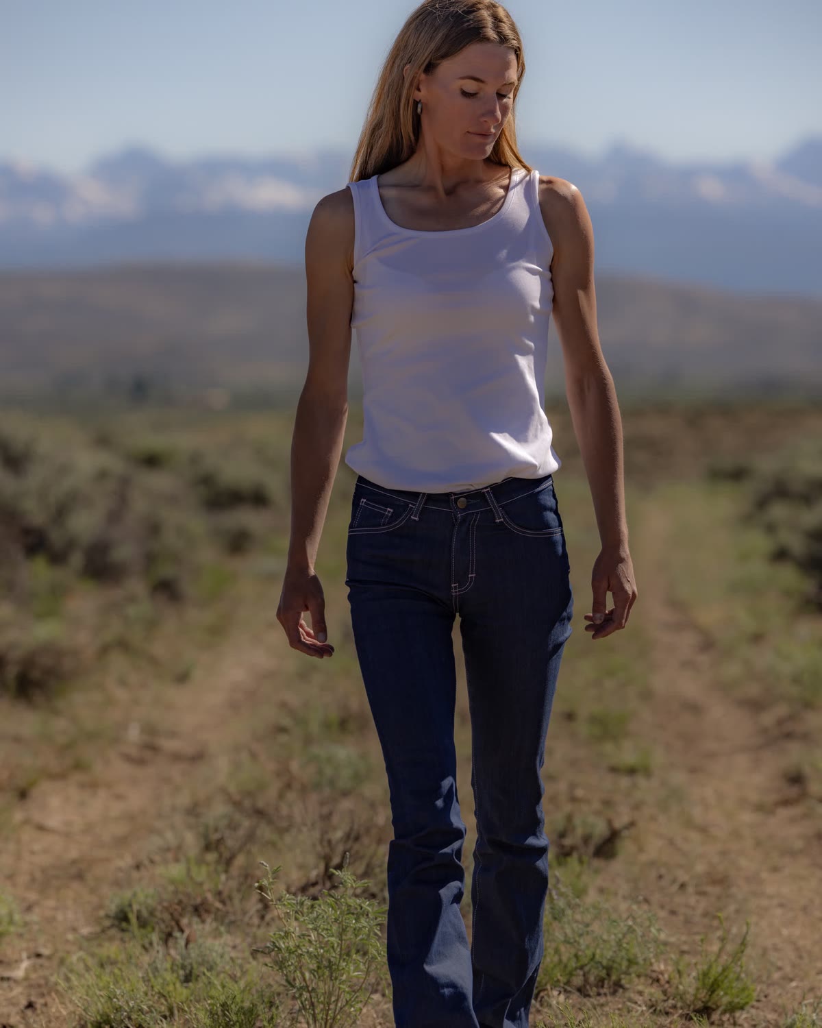 Woman in dark flare jeans walking a dirt track