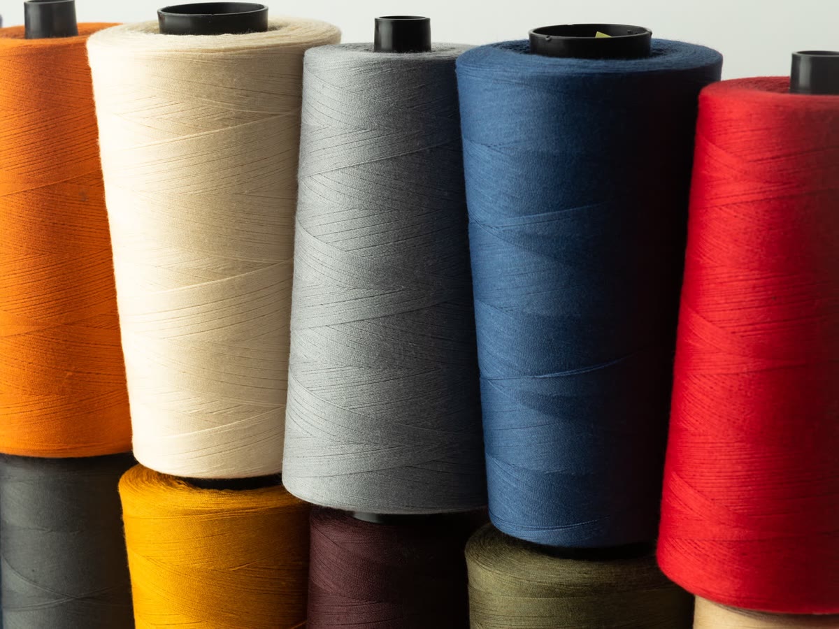 Spools of thread in a rack of colors, from orange and cream to blue and red