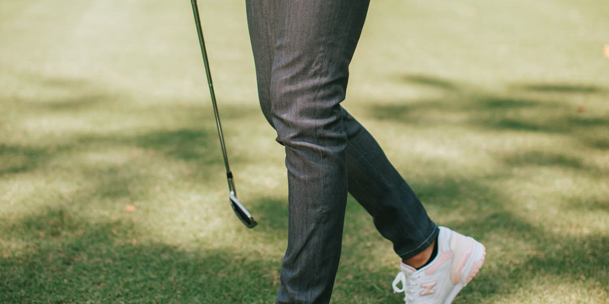 Gray performance pants and white sneakers walking the fairway with a club