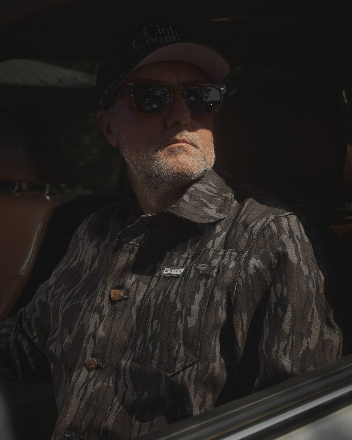 Men's Bottomland canvas jacket with copper buttons and Blue Delta chest tab, worn in a car.