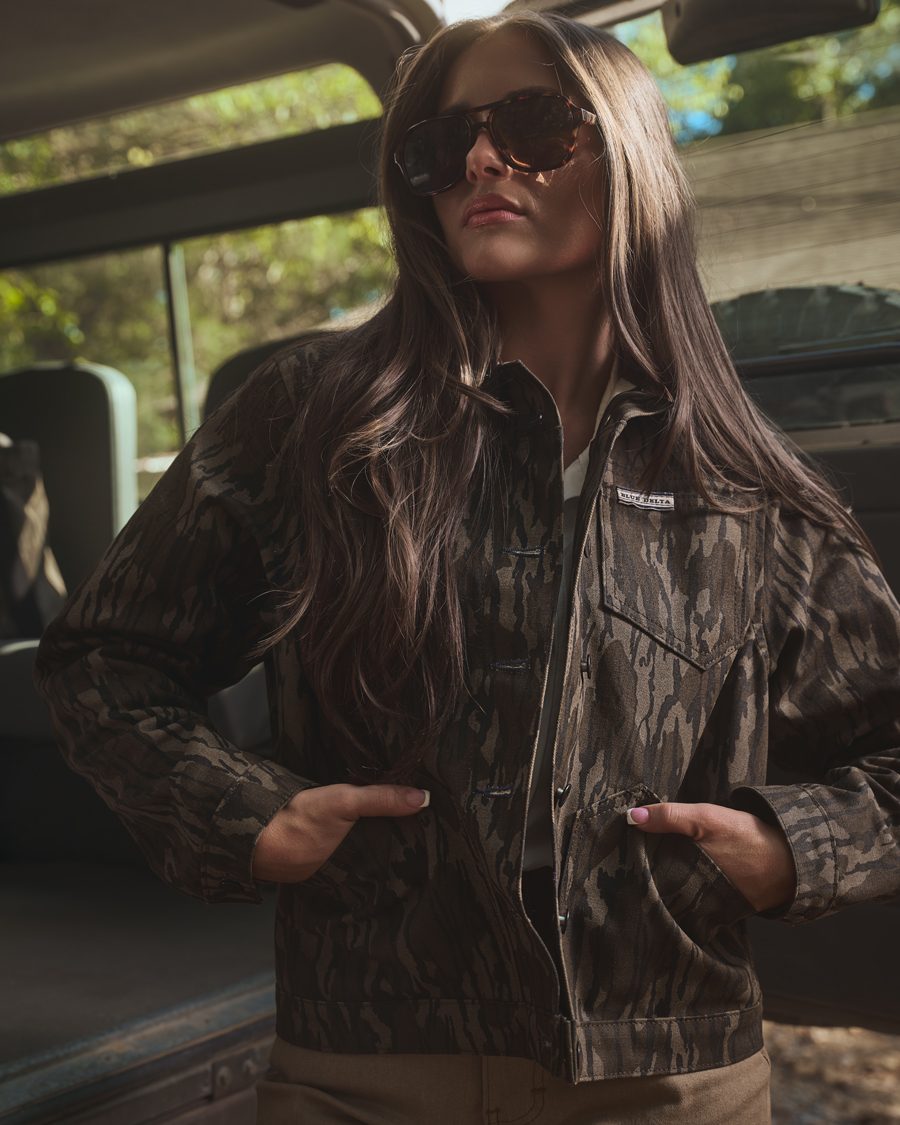 Women's Bottomland canvas jacket worn open with hands in the front pockets beside a vehicle.