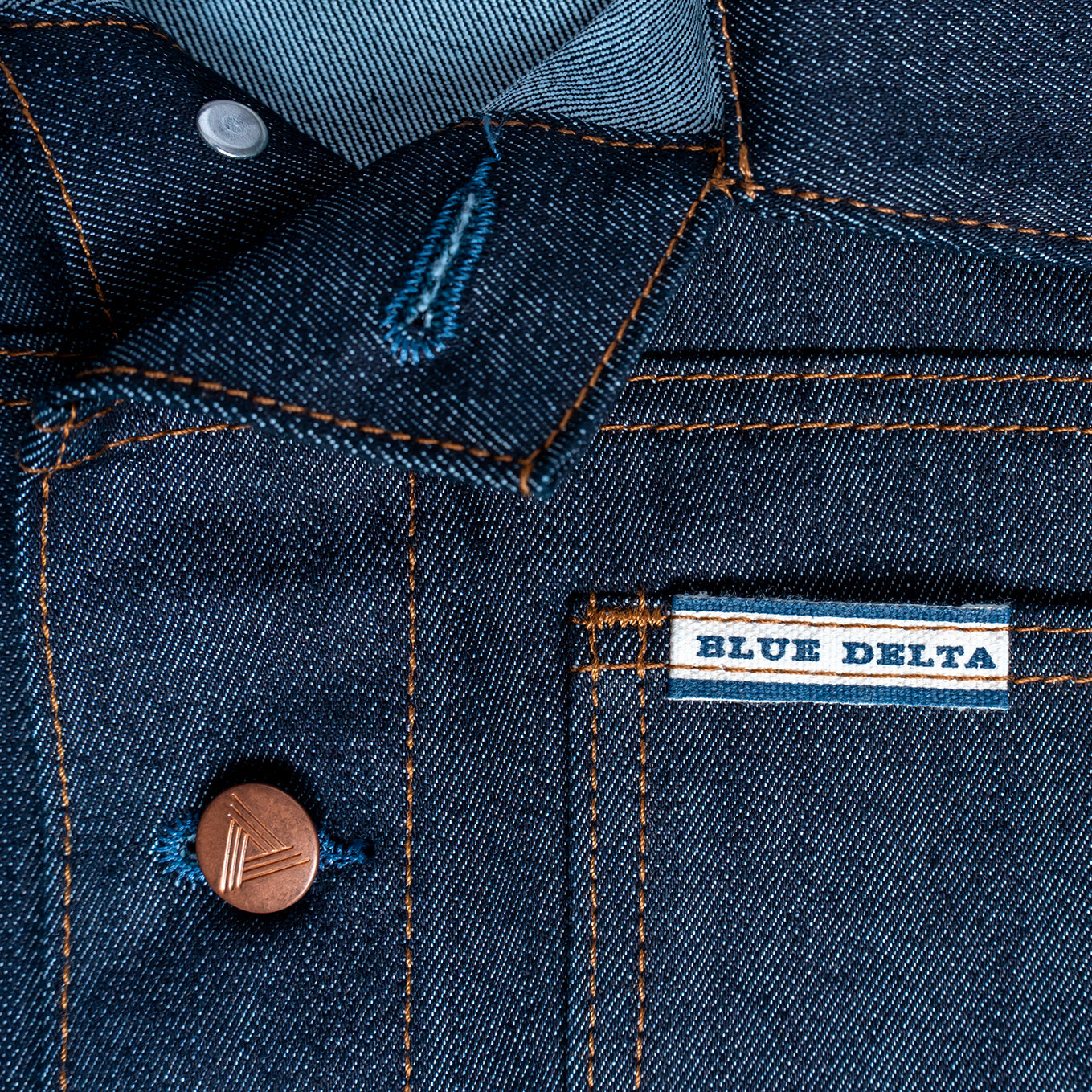 Close-up of a blue denim jacket with 'Blue Delta' label.