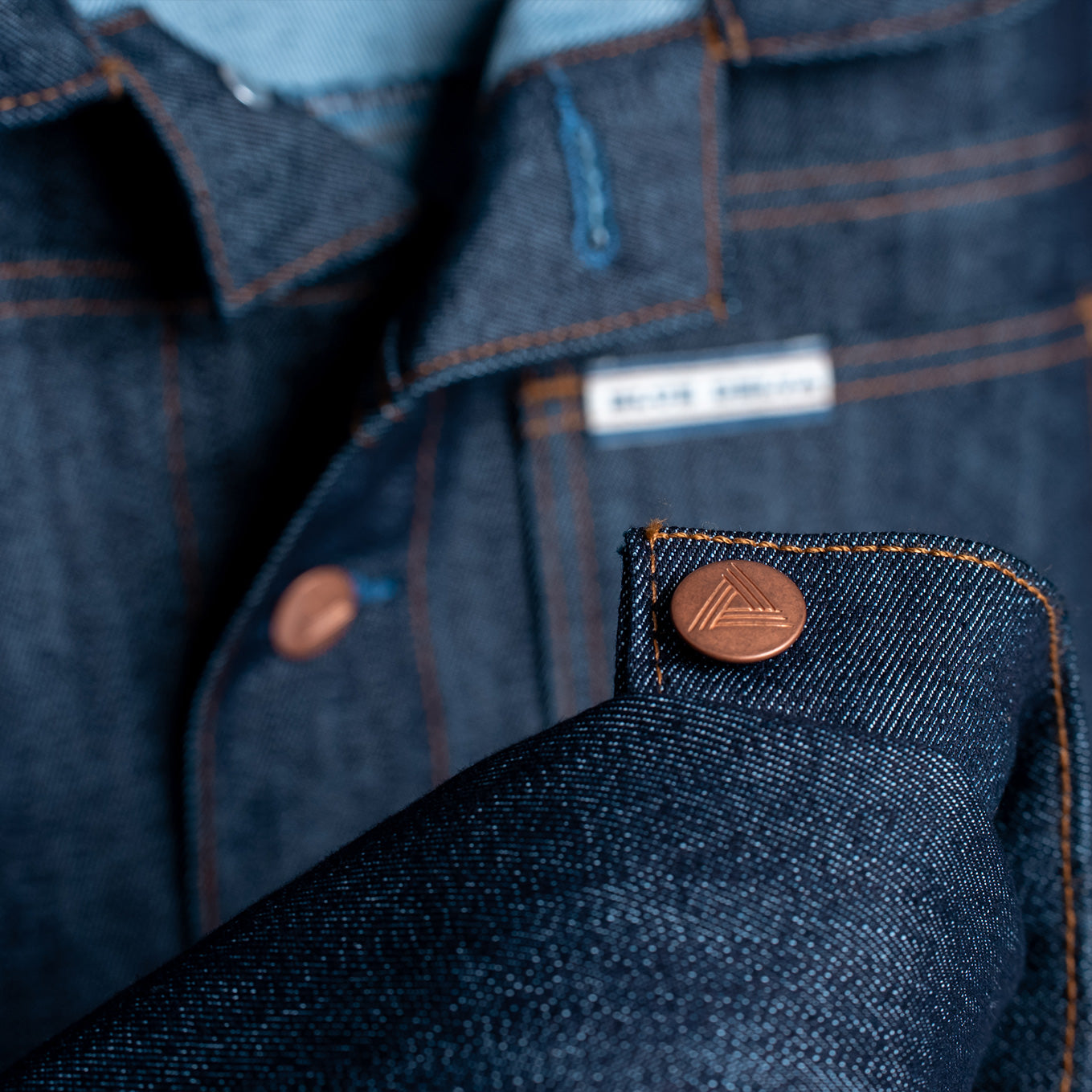 Close-up of dark indigo raw denim fabric on The Rancher jacket