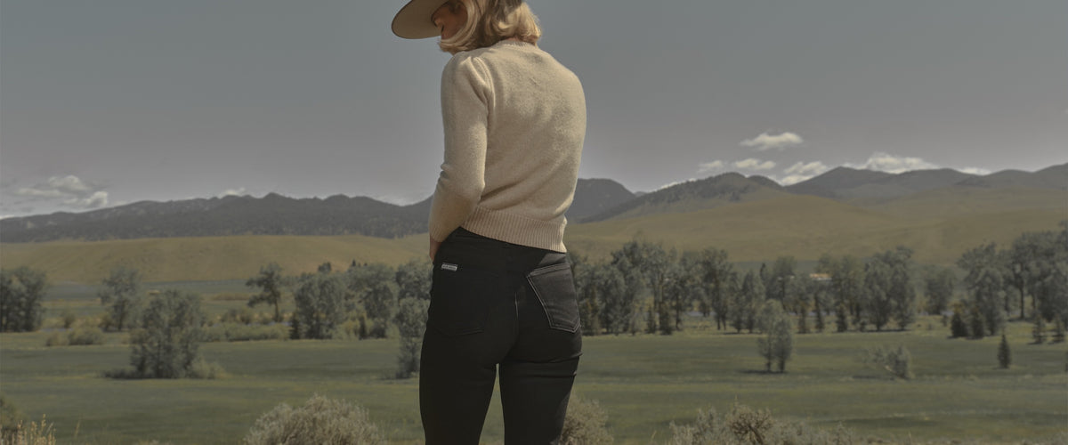 A woman in black flare jeans in a Montana valley