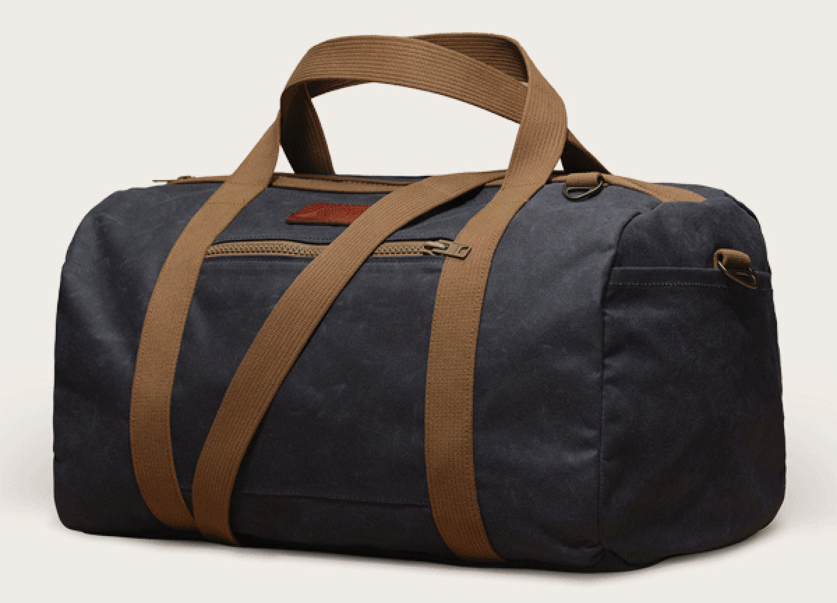 Navy wet-waxed canvas duffle bag with tan webbing handles