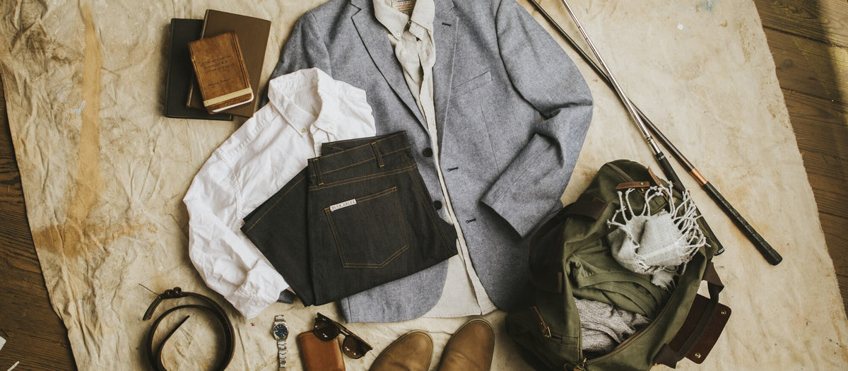A packed travel kit laid out: a shirt, a belt, shoes and a leather bag