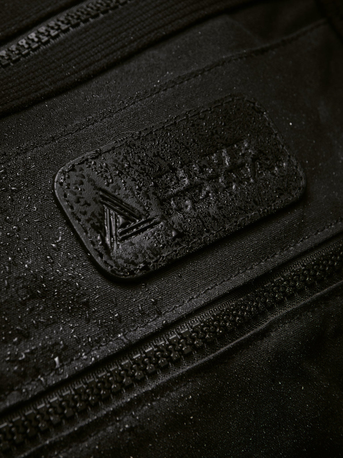Waxed Canvas Duffle in black: leather patch with water beading