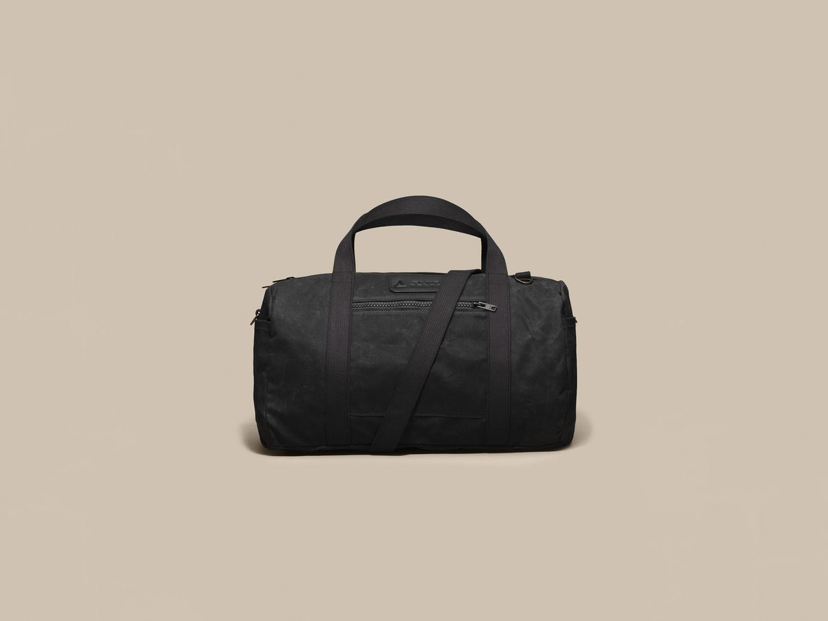 Waxed Canvas Duffle in black waxed canvas with black webbing and a black leather patch, front
