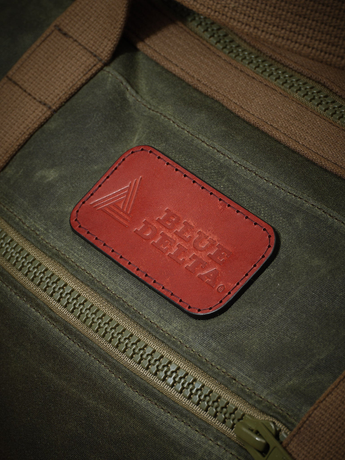 Waxed Canvas Duffle in green: leather logo patch and front zipper pocket