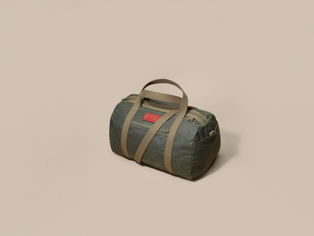 Waxed Canvas Duffle in green waxed canvas with green webbing and a Chestnut leather patch, three-quarter view