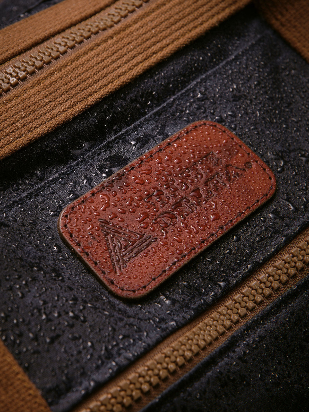 Waxed Canvas Duffle in navy: leather patch with water beading