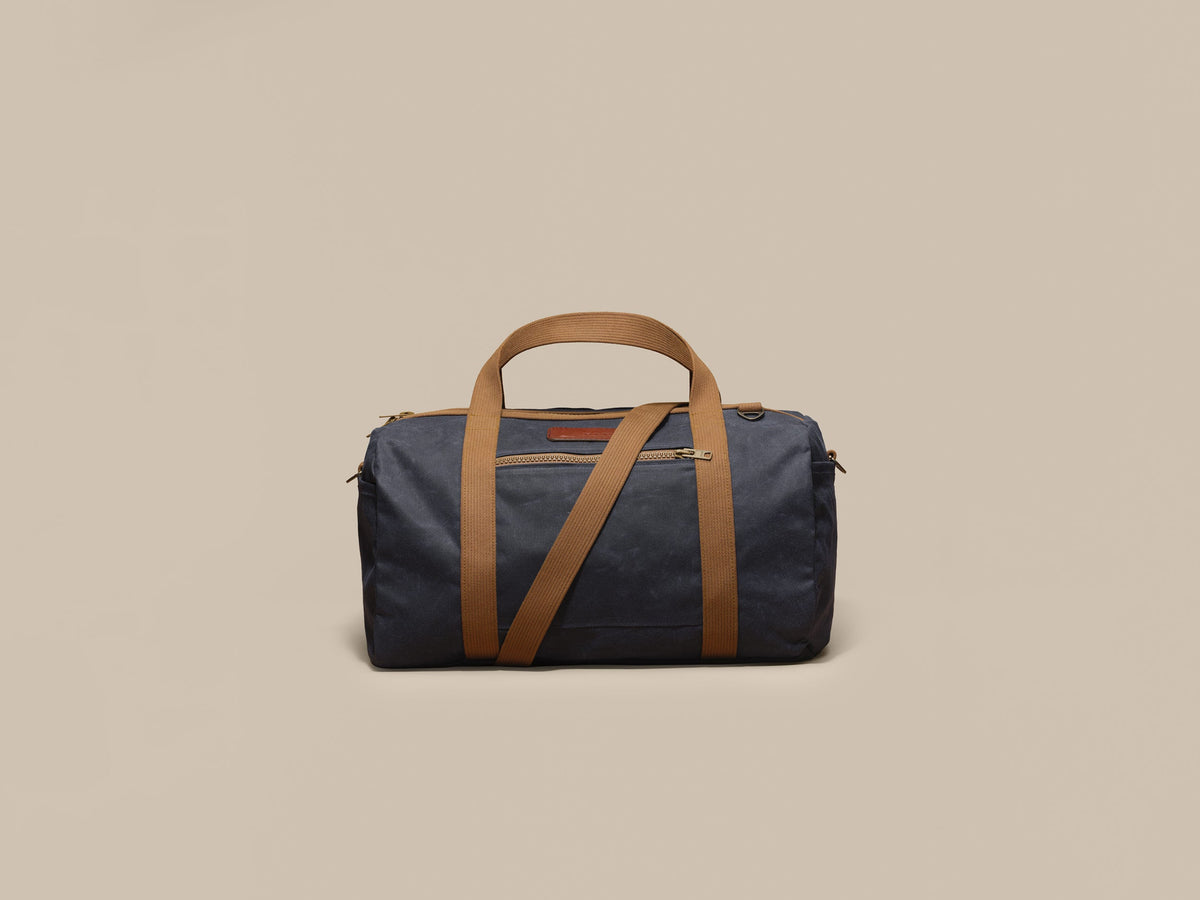 Waxed Canvas Duffle in navy waxed canvas with tan webbing and a Rich Brown leather patch, front
