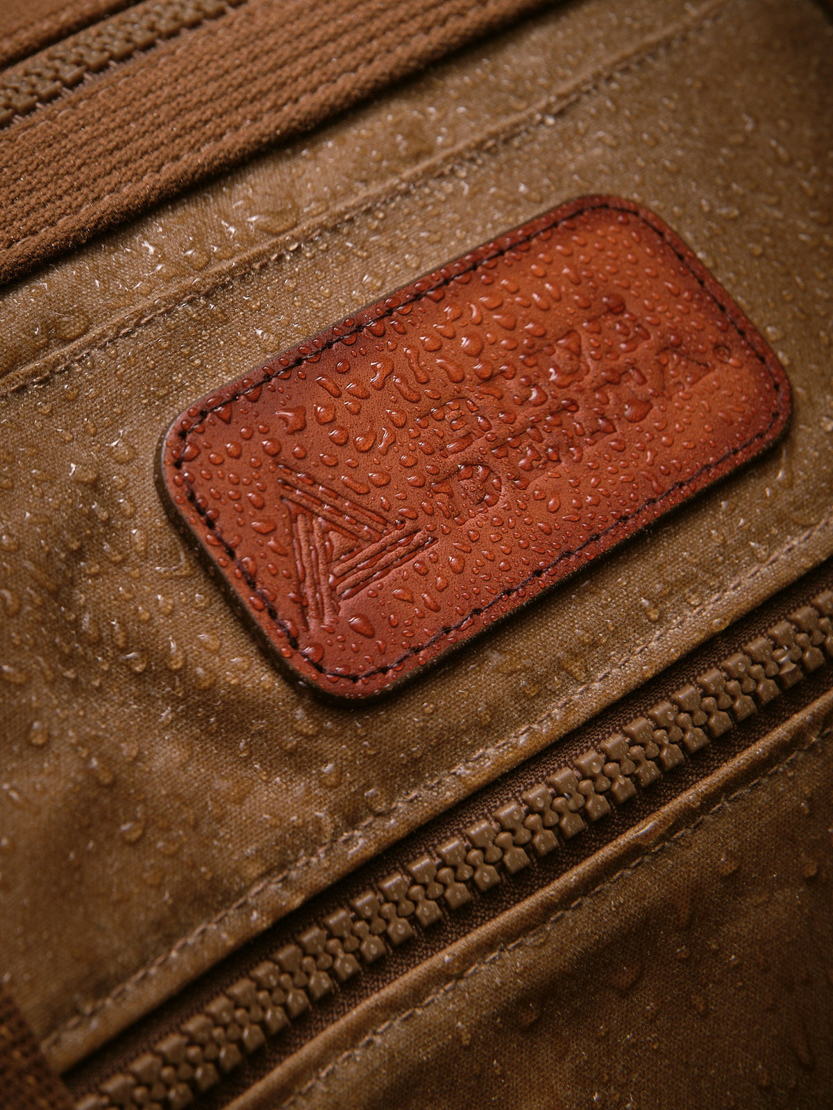 Waxed Canvas Duffle in tan: leather patch with water beading