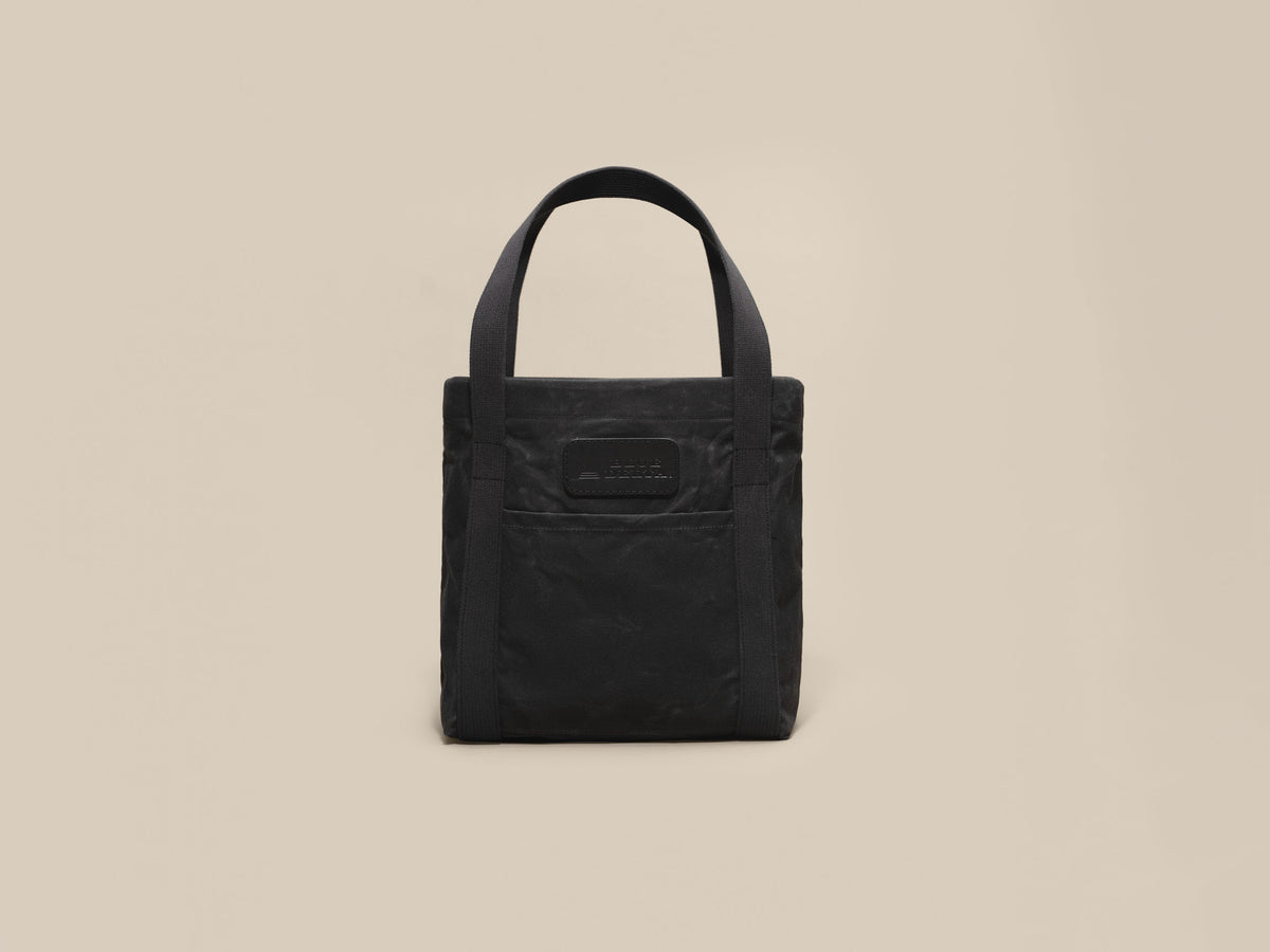 Waxed Canvas Tote in black waxed canvas with black webbing and a black leather patch, patch side