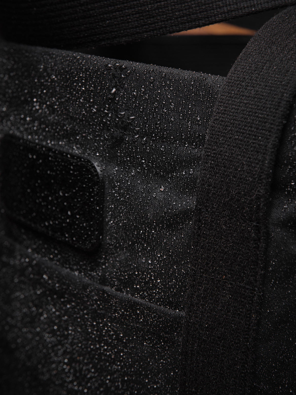 Waxed Canvas Tote in black: water beading on the canvas by the handle