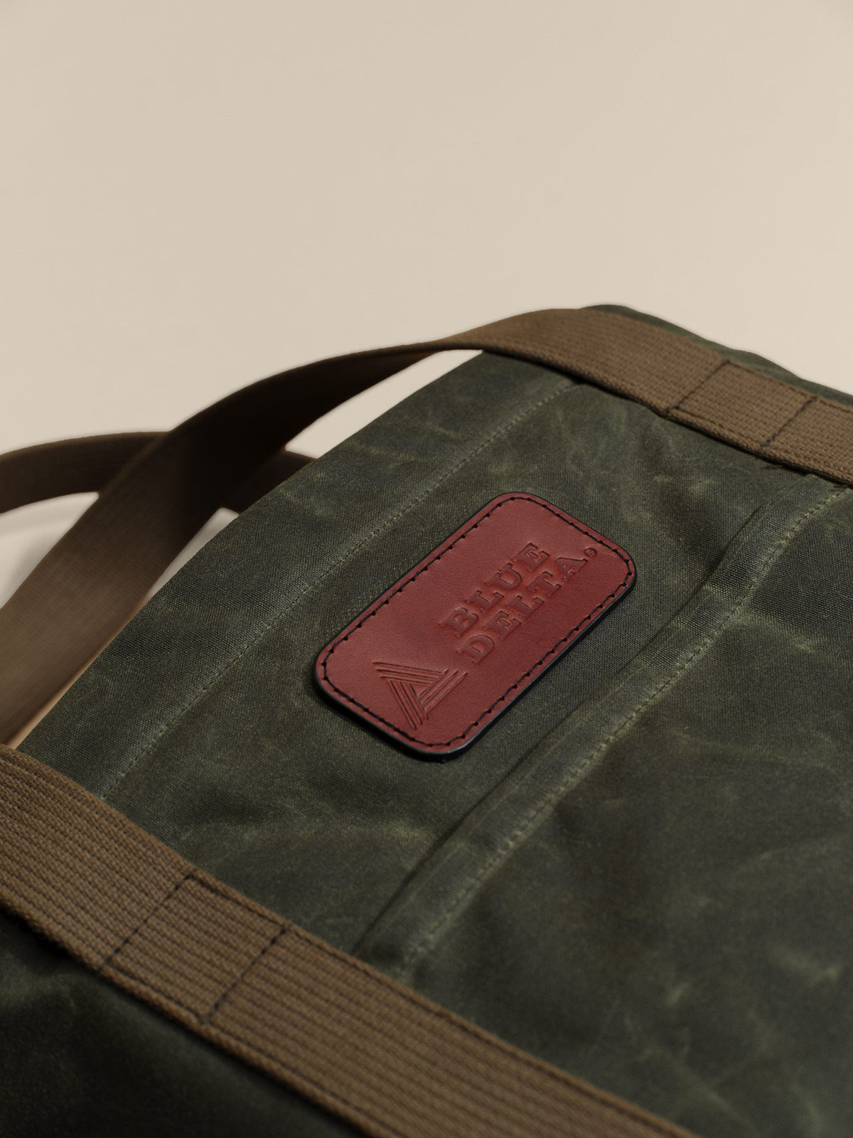 Waxed Canvas Tote in green: leather logo patch close-up
