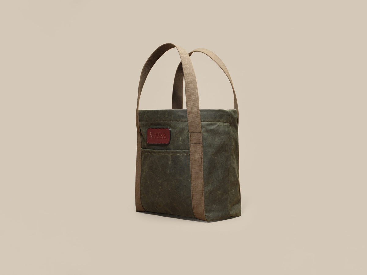 Waxed Canvas Tote in green waxed canvas with green webbing and a Chestnut leather patch, angled view