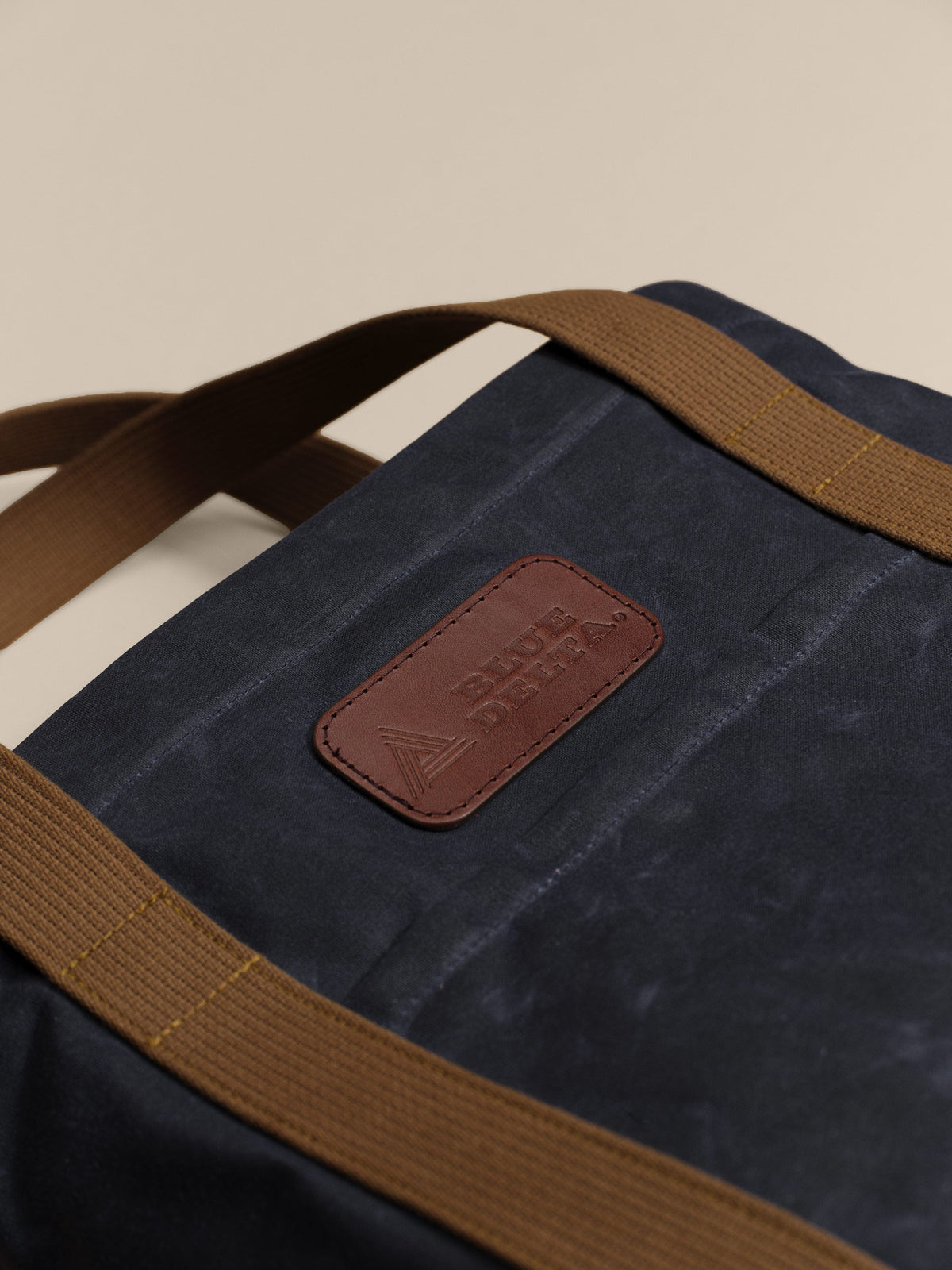 Waxed Canvas Tote in navy: leather logo patch close-up