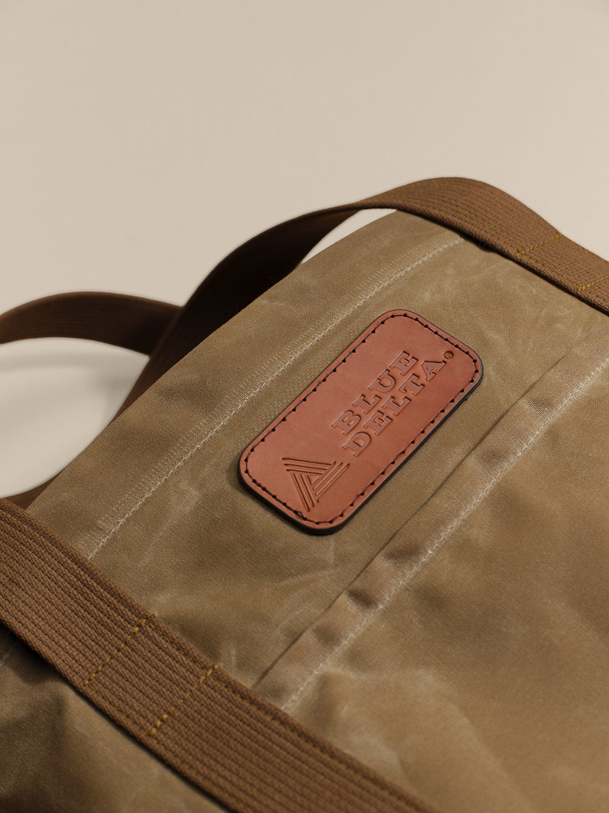 Waxed Canvas Tote in tan: leather logo patch close-up