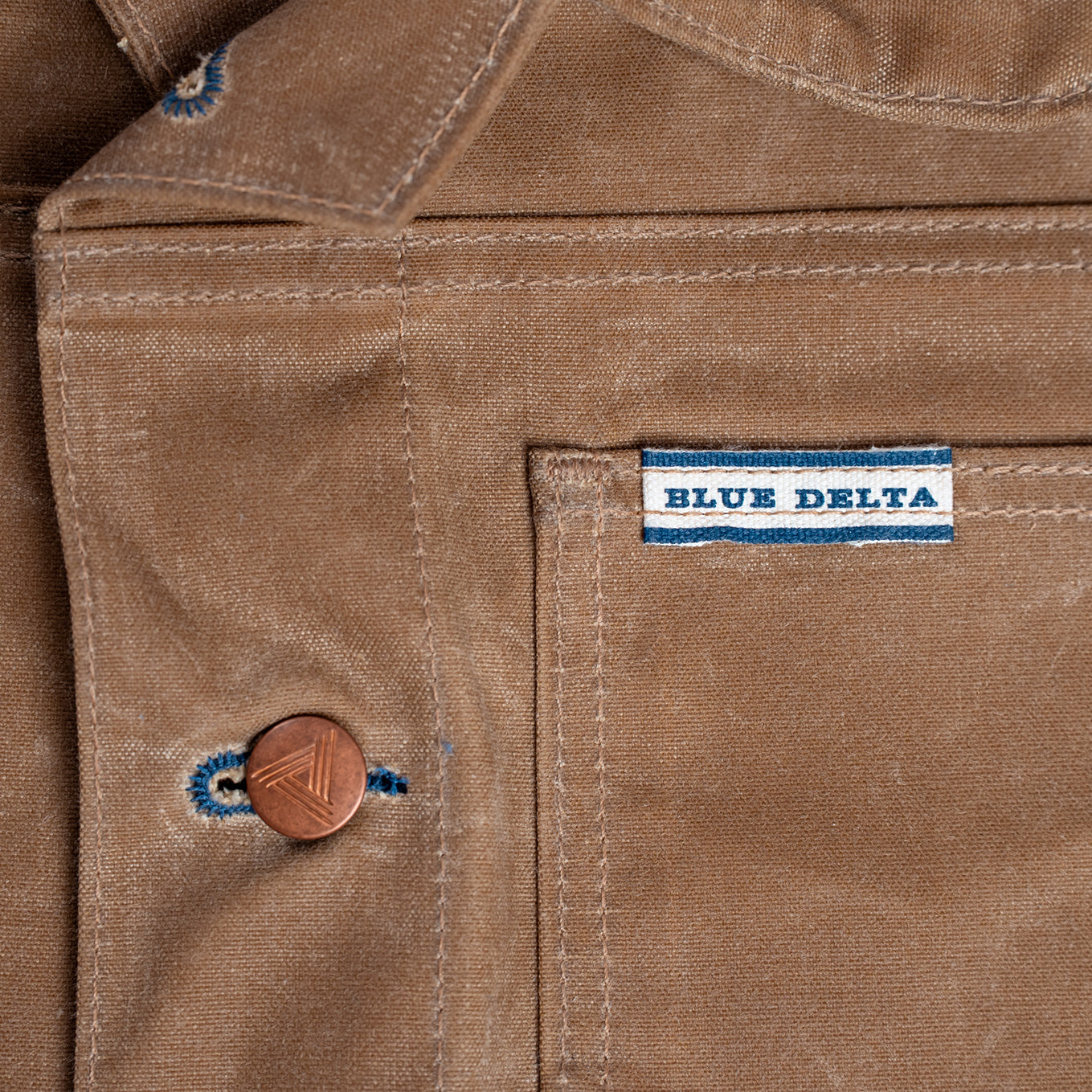 Close-up of the tan waxed fabric with a 'Blue Delta' label.