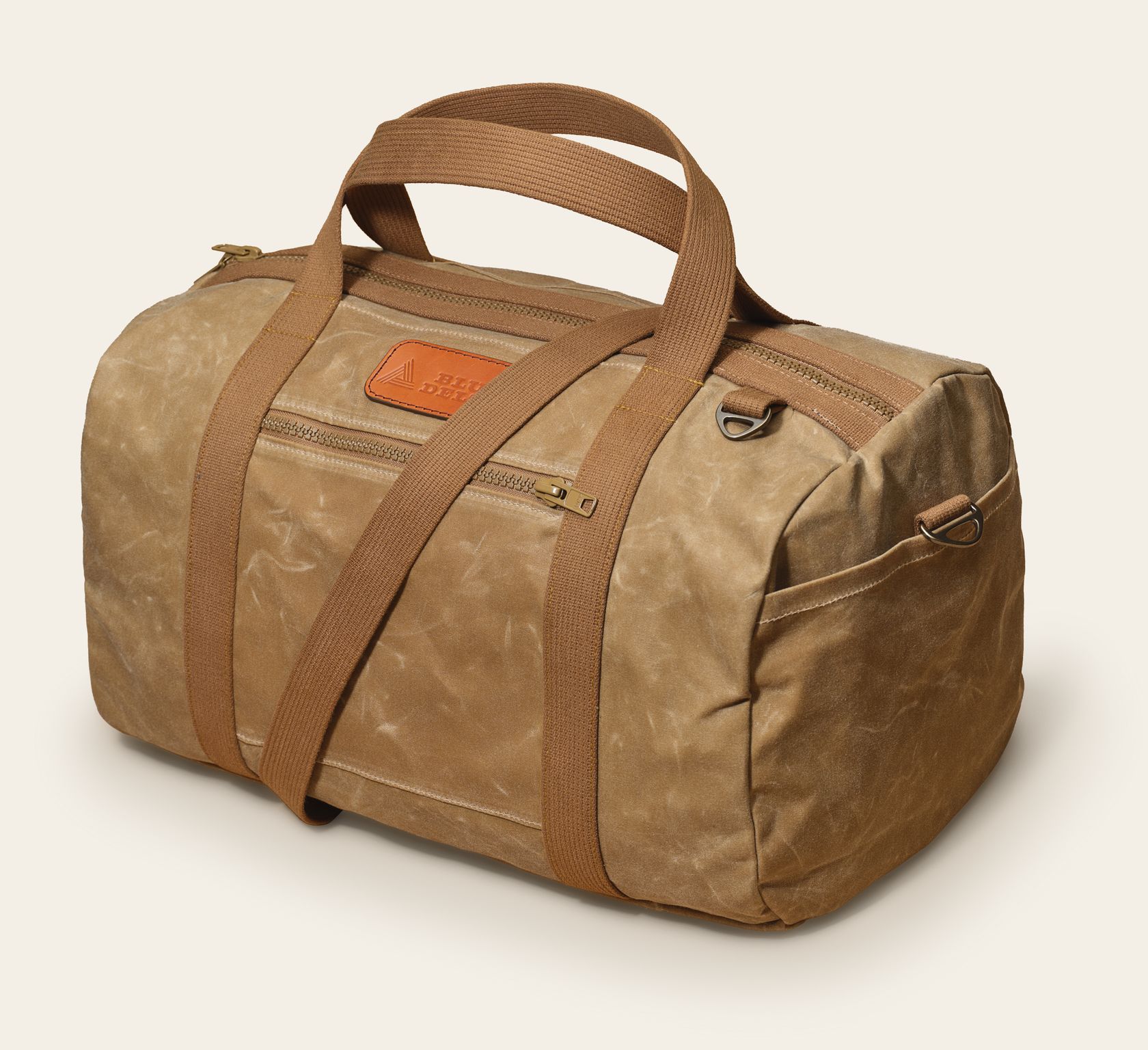 The Waxed Canvas Duffle in tan waxed canvas with tan webbing and a leather logo patch